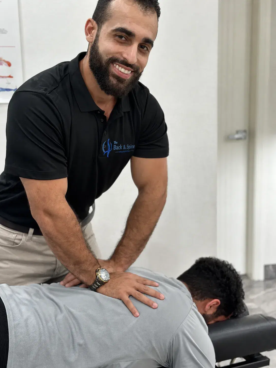 Dr Laith Musallam's hands during a lower-back adjustment, the patient lying face down.